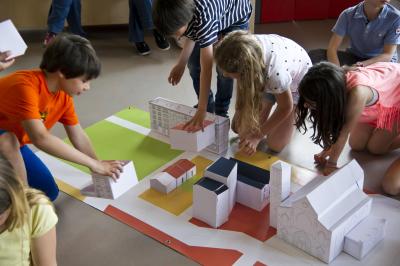Photographie d'enfants construisant une ville avec des maisons en papier